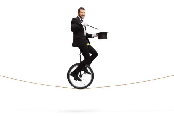 istock Magician performing a magic trick with a wand on a unicycle 1205966644