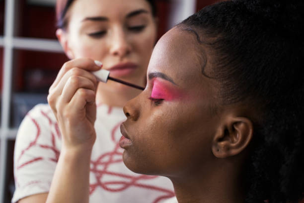 istock Make up artist doing makeup for african fashion model in studio 1205967454