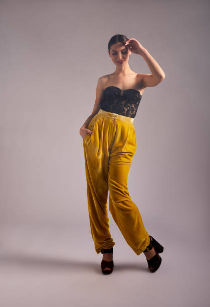 istock Smiling woman in a stylish outfit looking down on a colored background 1205970646