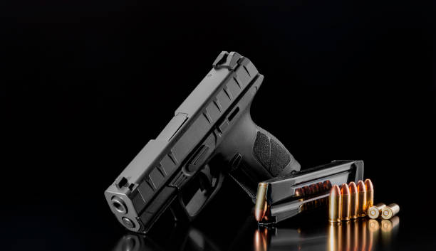 istock Black modern pistol and ammunition for it on adark  background. Short-barreled weapons for sports and self-defense. Armament for police units, special forces and the army. 1205971071