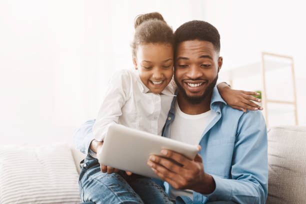 istock Family time. Young father teaching daughter to use digital tablet 1205972413