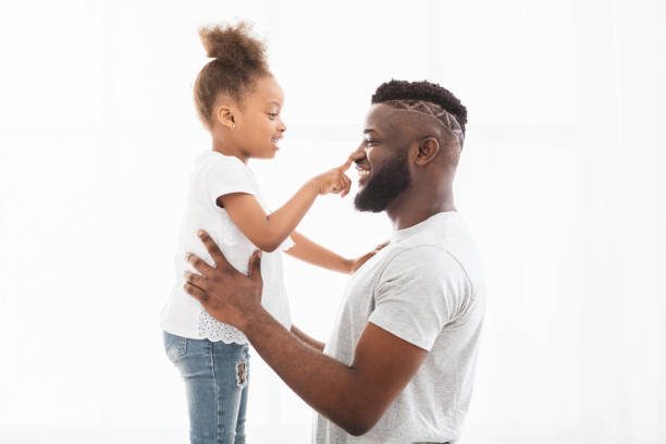 istock Curious afro girl touching her dad nose 1205972517