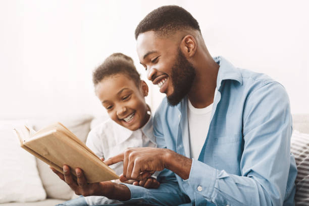 istock Caring african-american daddy reading book to his cute daughter 1205972583