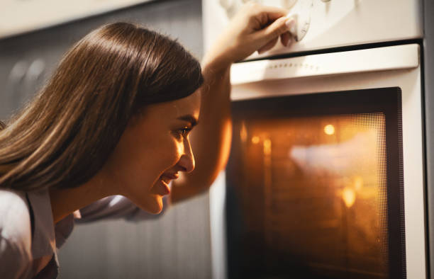 istock Cheerful housewife baking lunch in oven, setting temperature 1205972620