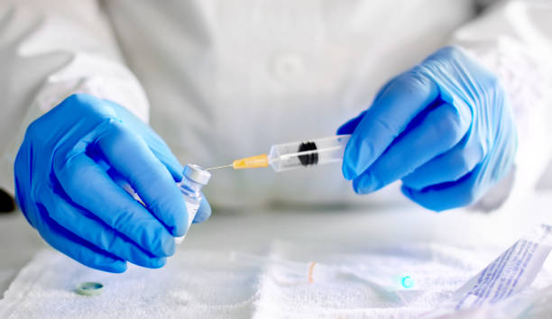 le docteur remplit la seringue d’injection avec le vaccin - virus laboratory biotechnology cell photos et images de collection