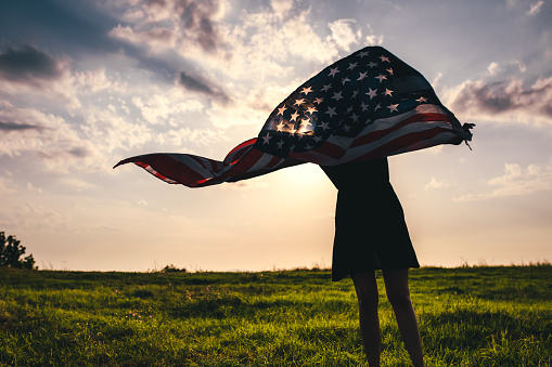 Gypsy young woman waving USA flag outdoor.