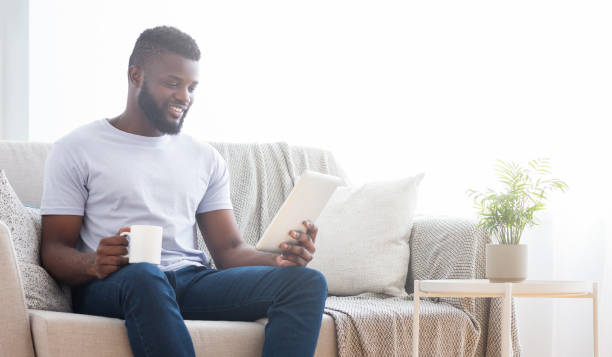 istock African man with morning coffee reading news on tablet 1205974973