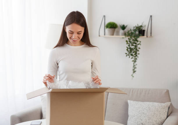 istock Smiling millennial girl opening cardboard delivery package 1205975565