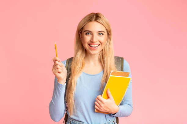 blonge teenager-mädchen halten stift und notebook im rosa studio - nerd computer learning fun stock-fotos und bilder