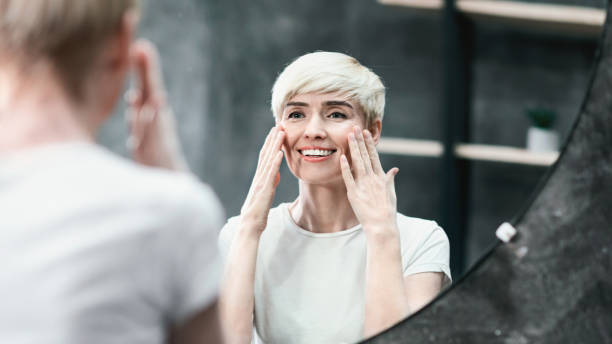 istock Happy Woman Touching Skin Under Eyes Looking In Mirror, Panorama 1205978433