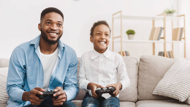 istock Happy afro dad enjoying video game with his cute daughter 1205978472