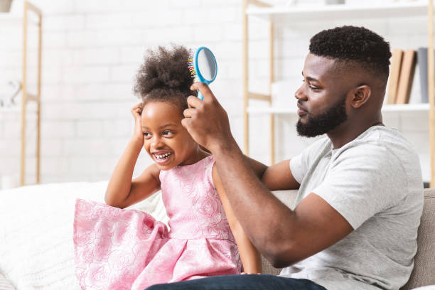 istock Handsome young man combing his little daughter hair 1205978835