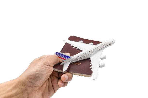 istock Hand holding a model plane and passport isolated on white background.Transportation and traveling with airplane concept. Close up with Clipping Path. 1205982667