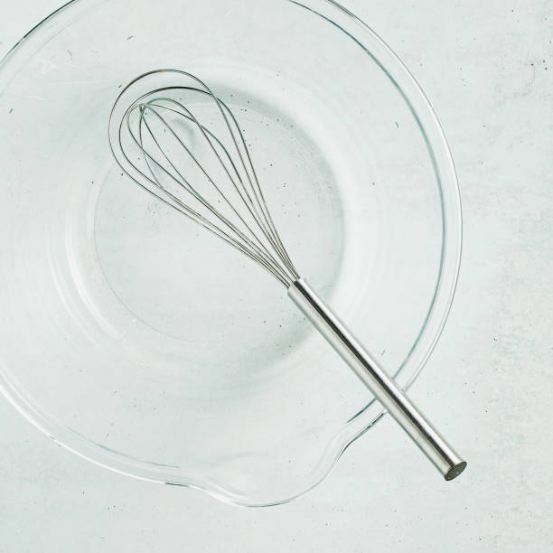 istock kitchen whisk in an empty glass bowl on the table. food background 1205982754