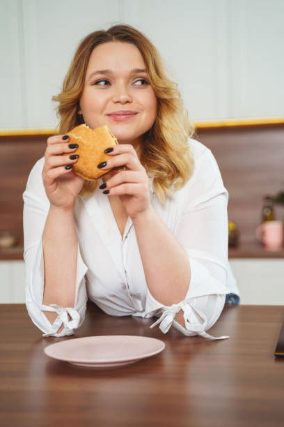 istock Joyful blonde girl having burger for dinner 1205983379