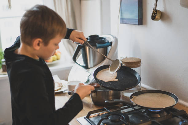 istock Young boy frying pancakes 1205983882