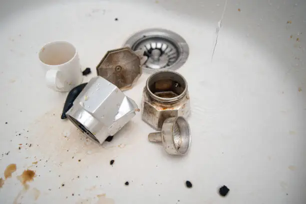 Disassembled coffeemaker, dirty mug and stains on the surface of kitchen sink