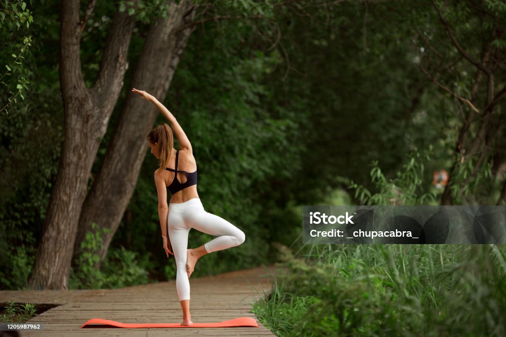 Pretty girl doing yoga and stretching outdoors in green park Beautiful slim young woman doing yoga and stretching outdoors in green park Adult Stock Photo
