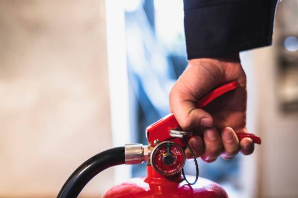 image of man checking a fire extinguisher stock photo
