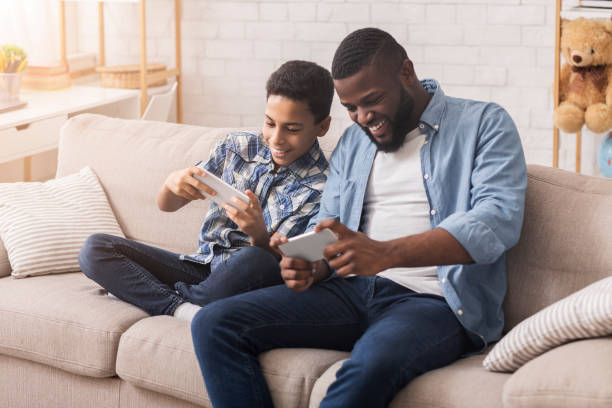 istock Happy Black Father And Son Playing Videogames On Smartphone Together 1205991741