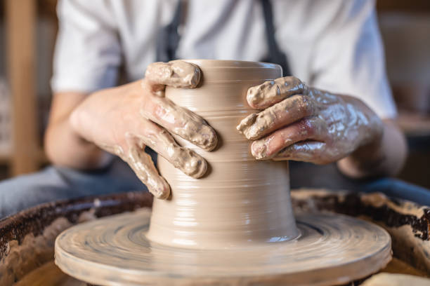 istock Potter working on a Potter's wheel making a vase. Woman forming the clay with hands creating jug in a workshop. Close up 1205993500
