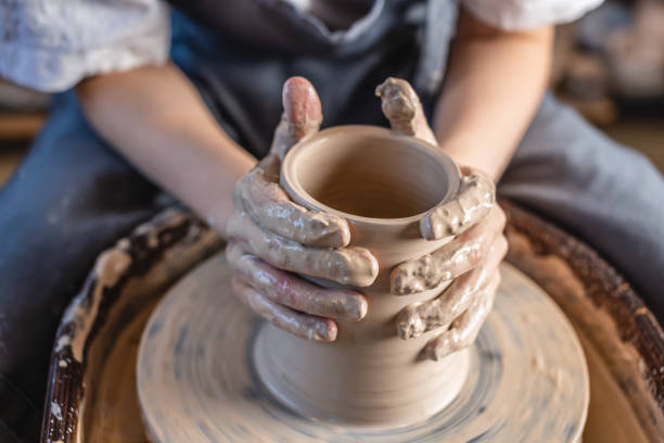 istock Potter working on a Potter's wheel making a vase. Woman forming the clay with hands creating jug in a workshop. Close up 1205993792