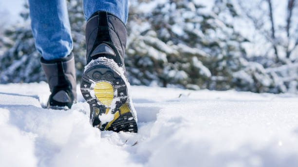 botas de invierno masculinas o femeninas caminando en la carretera nevada - prepared sole fotografías e imágenes de stock