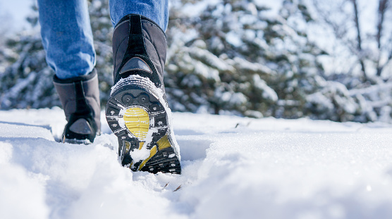 male or female winter boots walking on snowy sleet road