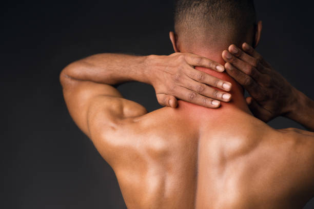Shirtless black man suffering from pain in neck Sports Injury. Back view of naked black man suffering from pain in neck, symptom of cervical chondrosis, red spot black male massage stock pictures, royalty-free photos & images