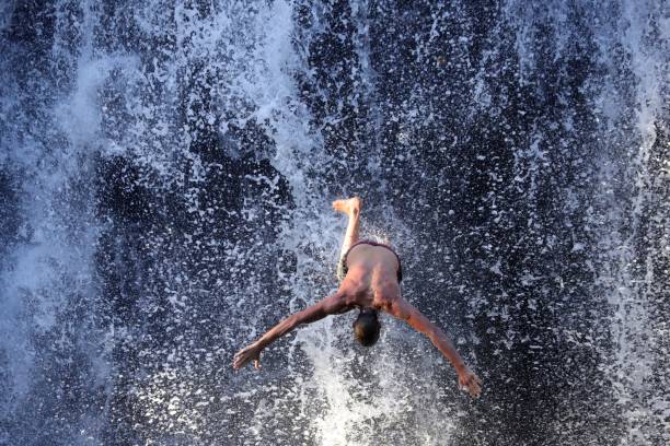 Souillac, Mauritius - September 25, 2019: Young Man jumps from the spectacular 10 m high Rochester Waterfall in the South of Mauritius.