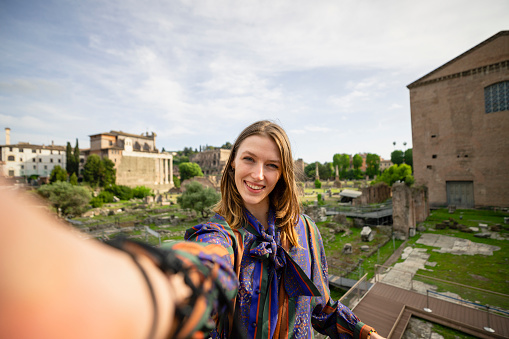 A selfie a young woman in front of old ruins while on holiday in Rome, Italy.