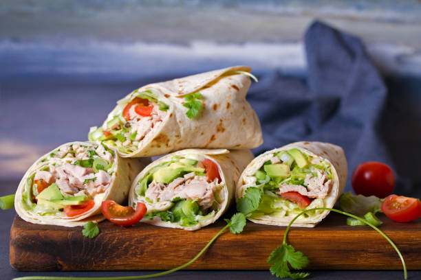Turkey wraps with avocado, tomatoes and iceberg lettuce on chopping board Turkey wraps with avocado, tomatoes and iceberg lettuce on chopping board. Tortilla, burritos, sandwiches, twisted rolls wrap sandwich photos stock pictures, royalty-free photos & images