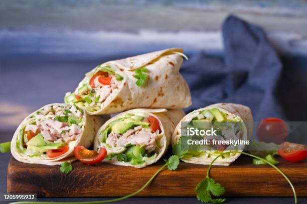 Turkey Wraps With Avocado Tomatoes And Iceberg Lettuce On Chopping Board Stock Photo - Download Image Now