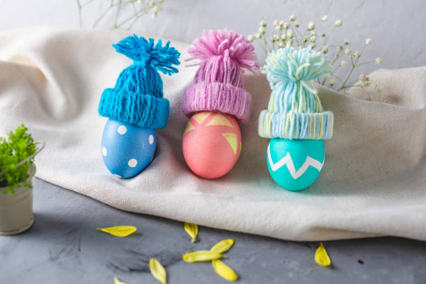 istock Bright colorful Easter eggs in a knitted winter hats on a gray background. Festive spring Easter card 1205996336