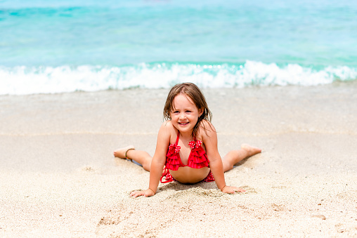 Cute little girl is laying by the water and smiling, looking at camera