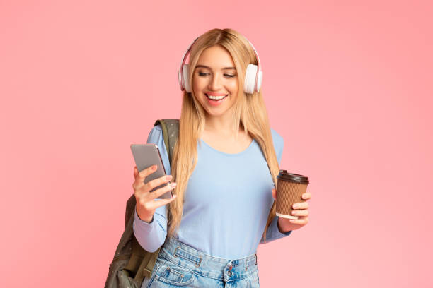 istock Teenager with headphones and backpack at pink studio 1205999561
