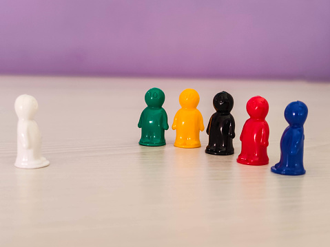 Conception  - lidership, leader in a team, diversity, game figures or pawns in a business situation. Colored chips of tabletop game in the little men form