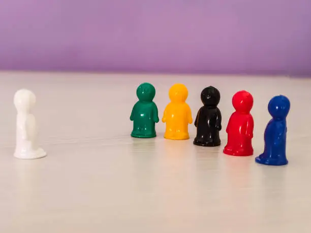Photo of Conception  - lidership, leader in a team, diversity, game figures or pawns in a business situation. Colored chips of tabletop game in the little men form