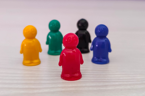Conception  - lidership, leader in a team, diversity, game figures or pawns in a business situation. Colored chips of tabletop game in the little men form