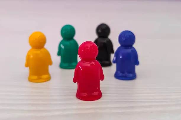 Photo of Conception  - lidership, leader in a team, diversity, game figures or pawns in a business situation. Colored chips of tabletop game in the little men form