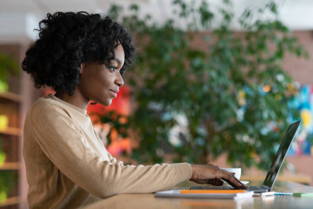 istock Young afro woman working in cafe, using laptop 1205999890