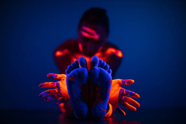 Body part painted with fluorescent makeup under the ultraviolet light Portrait of young woman with body painted with fluorescent makeup that glowing under the ultraviolet light. Photo taken under the real neon ultraviolet light (black light). High ISO value body paint stock pictures, royalty-free photos & images