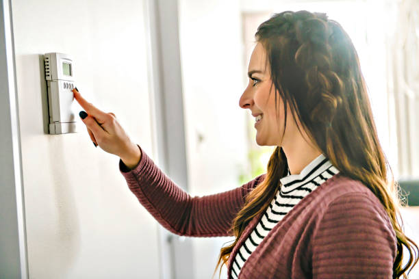 istock Smiling Woman Adjusting Thermostat On Home Heating System 1206002575