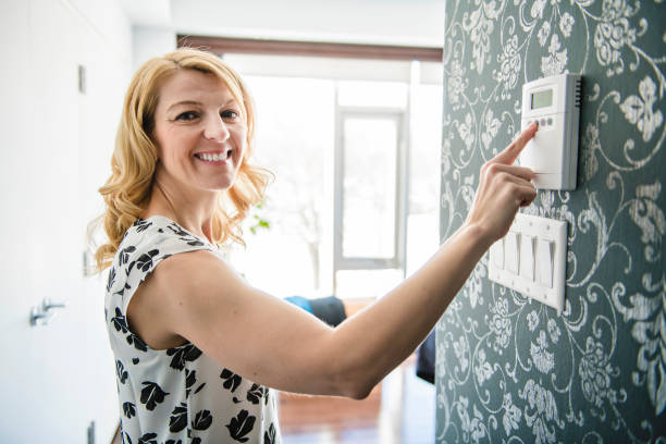 istock Smiling Woman Adjusting Thermostat On Home Heating System 1206003253