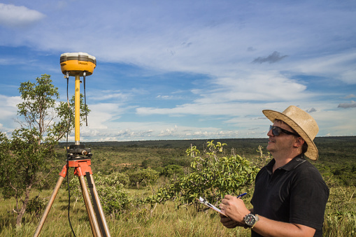 Topographic surveyor - Latin man writing down information from a gps receiver in rural area