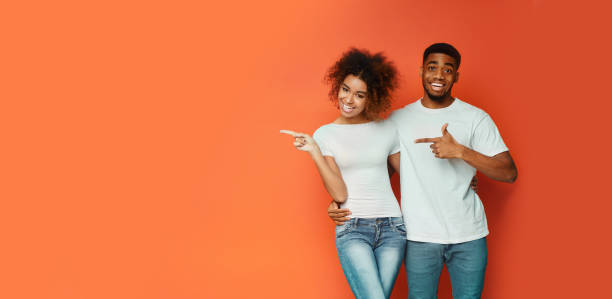istock African American Couple Pointing Fingers At Copyspace, Orange Background, Panorama 1206004711