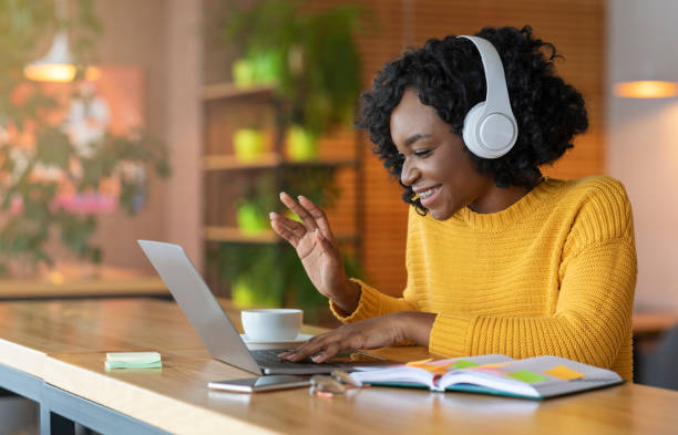 ragazza afro in cuffia usando laptop, con conferenza skype - folto foto e immagini stock