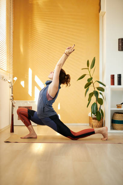 widok z boku atrakcyjnej brunetki w średnim wieku w warrior pozuję. wnętrze domu, poranna poranek. - posture women side view yoga zdjęcia i obrazy z banku zdjęć