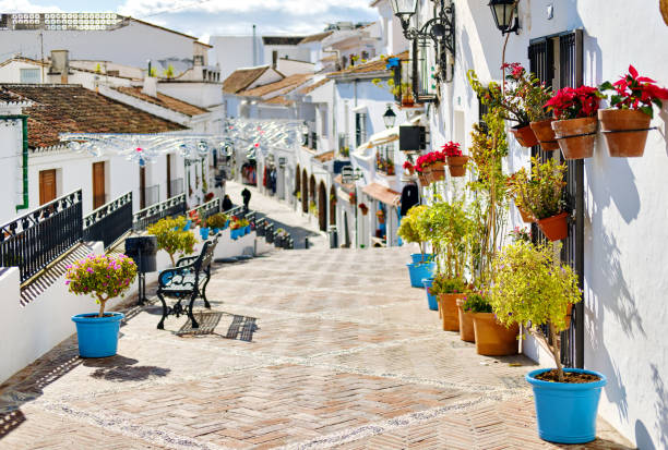 Idyllic scene picturesque street white-washed village of Mijas Idyllic scene picturesque street small white-washed village of Mijas. Path way decorated with hanging on houses walls plants in bright flowerpots, famous place Costa del Sol, Andalusia, Málaga, Spain andalusia stock pictures, royalty-free photos & images