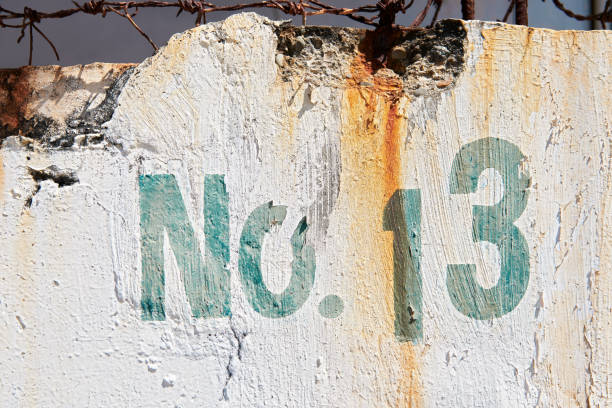 istock Faded house number thirteen on a dirty white wall 1206008801